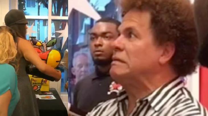 Romero Britto com cara de espanto ao ver sua peça sendo quebrada pela cliente.